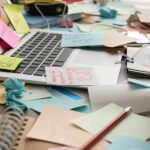 ordinatuer portable ouvert encombré de post-it,c arnets, crayons