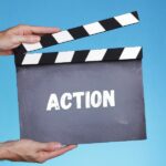deux mains d'homme tiennent un clap de cinema sur lequel il est écrit ACTION