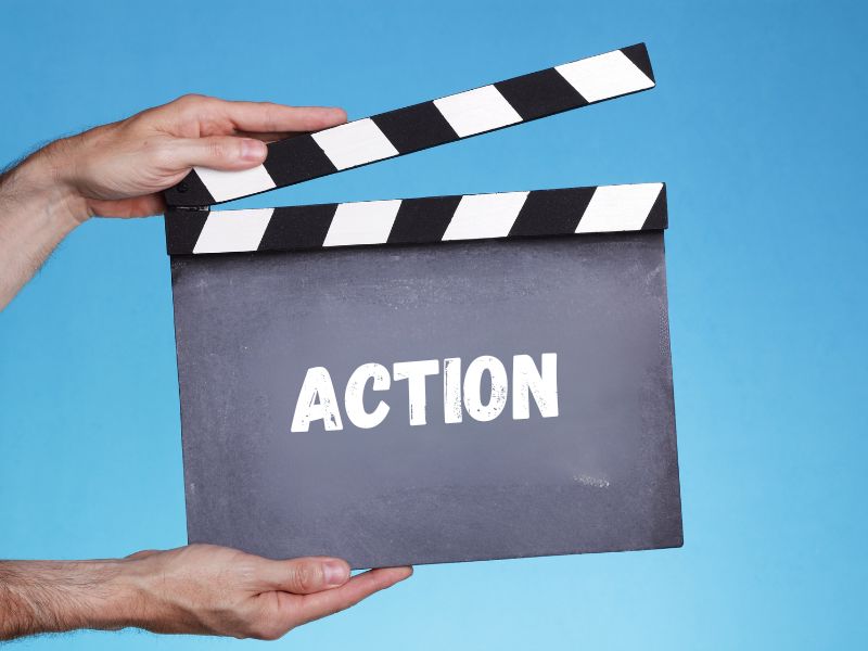 deux mains d'homme tiennent un clap de cinema sur lequel il est écrit ACTION
